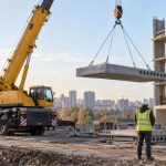 Автокран поднимает бетонную плиту на строительной площадке
