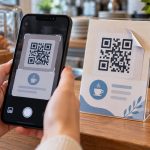 Смартфон біля умовного платіжного QR-коду з піднятим кутом наклейки
